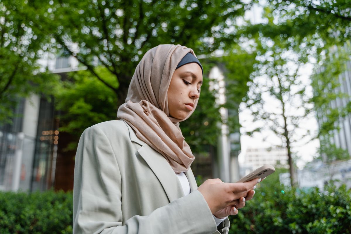 Une jeune femme regarde son téléphone dans un parc