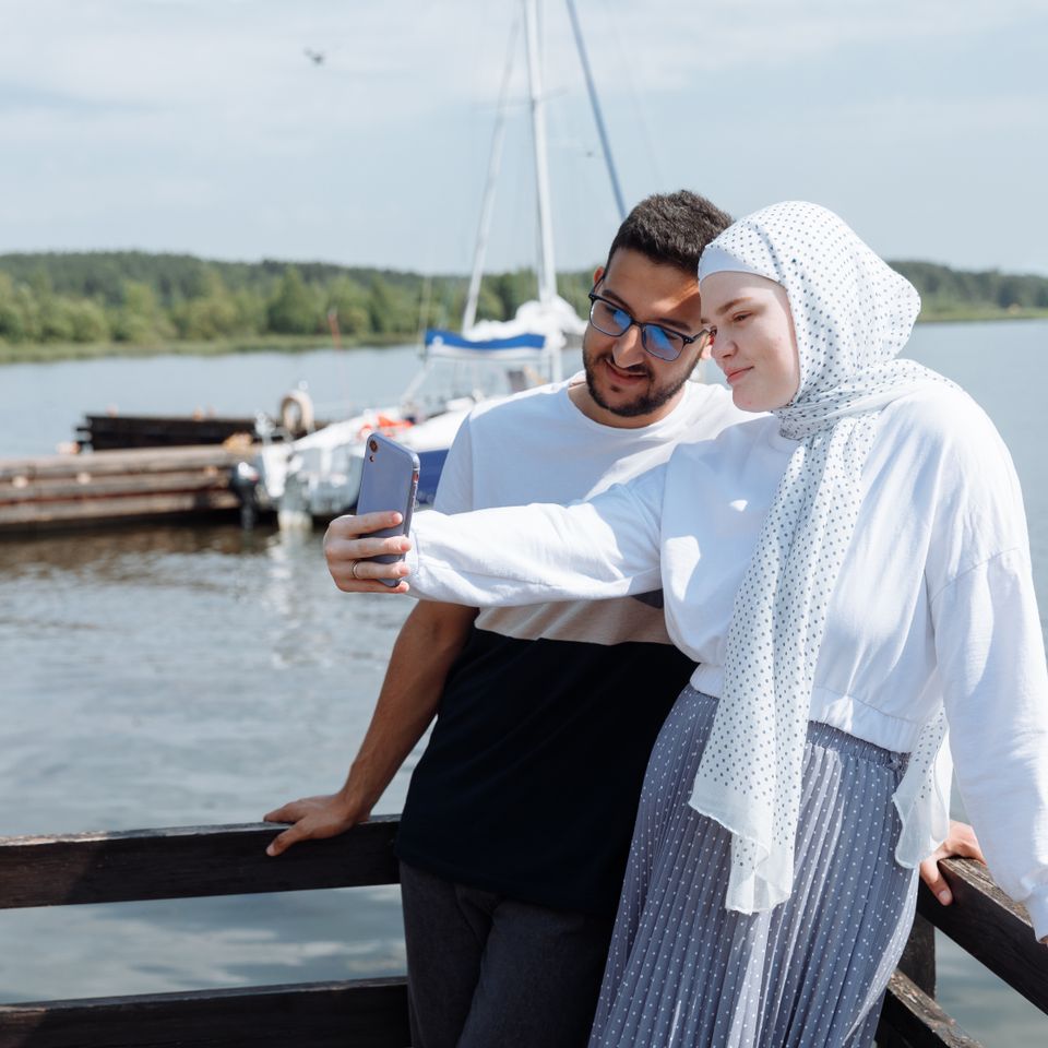 Un couple prend un selfie au bord d’un lac